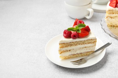 Photo of Piece of tasty sponge cake with fresh berries and mint served on light gray table, space for text