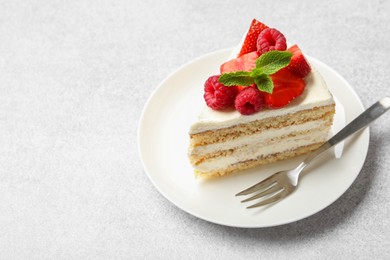 Piece of tasty sponge cake with fresh berries and mint served on light gray table, space for text