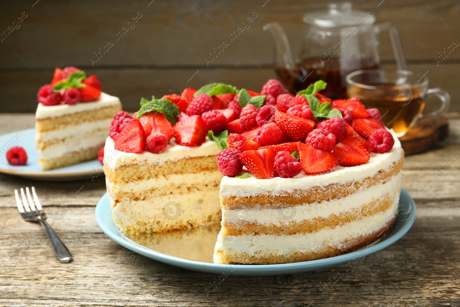 Photo of Tasty sponge cake with fresh berries and mint on wooden table, closeup