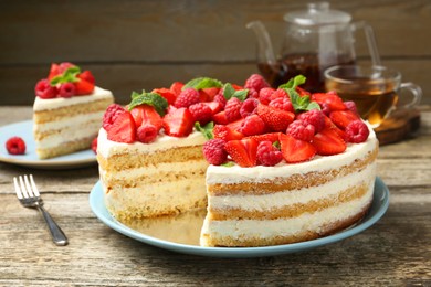 Photo of Tasty sponge cake with fresh berries and mint on wooden table, closeup