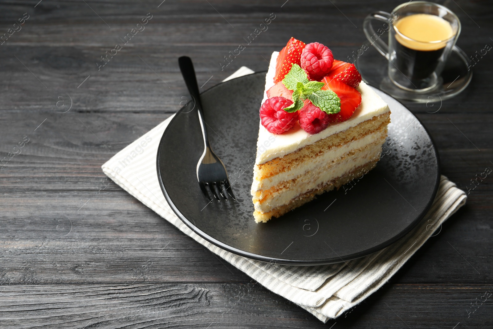 Photo of Piece of tasty sponge cake with fresh berries and mint served on black wooden table, space for text