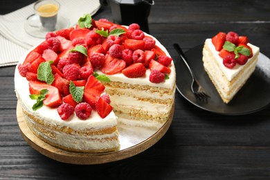 Photo of Tasty sponge cake with fresh berries and mint served on black wooden table