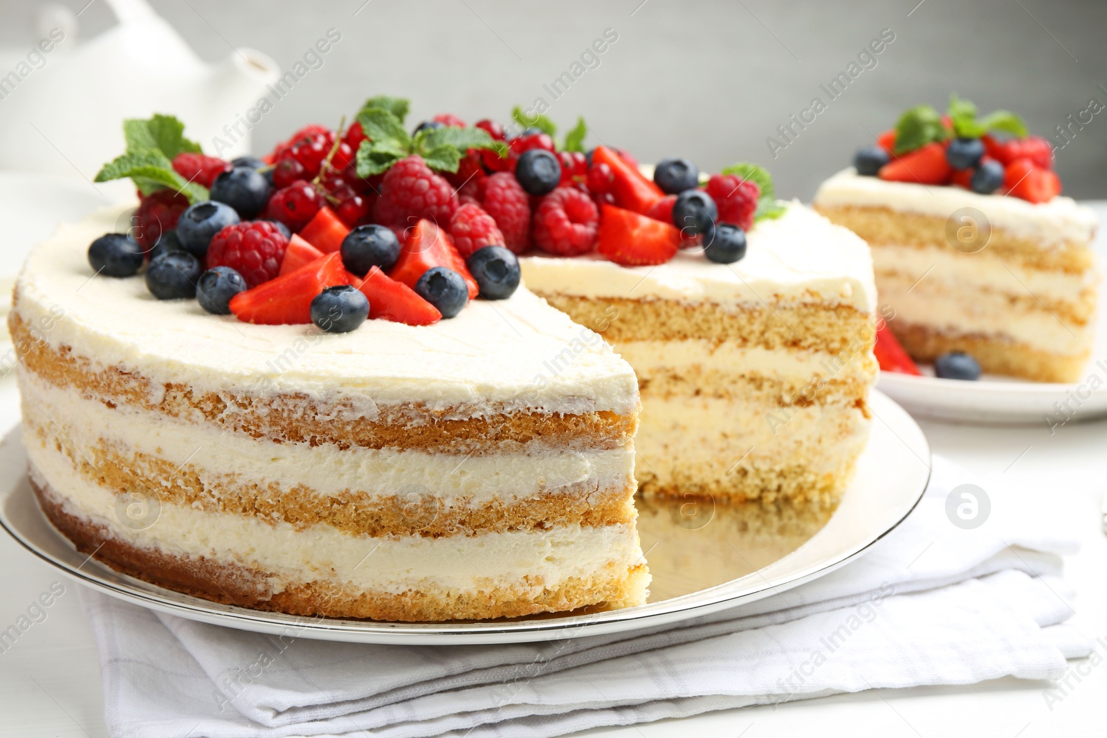 Photo of Tasty sponge cake with fresh berries and mint on white table, closeup