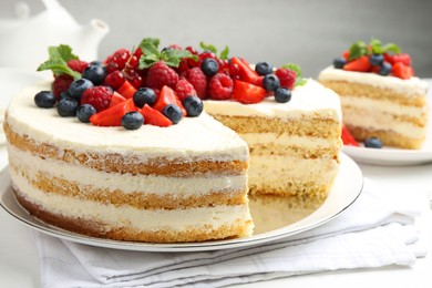 Photo of Tasty sponge cake with fresh berries and mint on white table, closeup