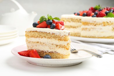 Photo of Tasty sponge cake with fresh berries and mint served on white table