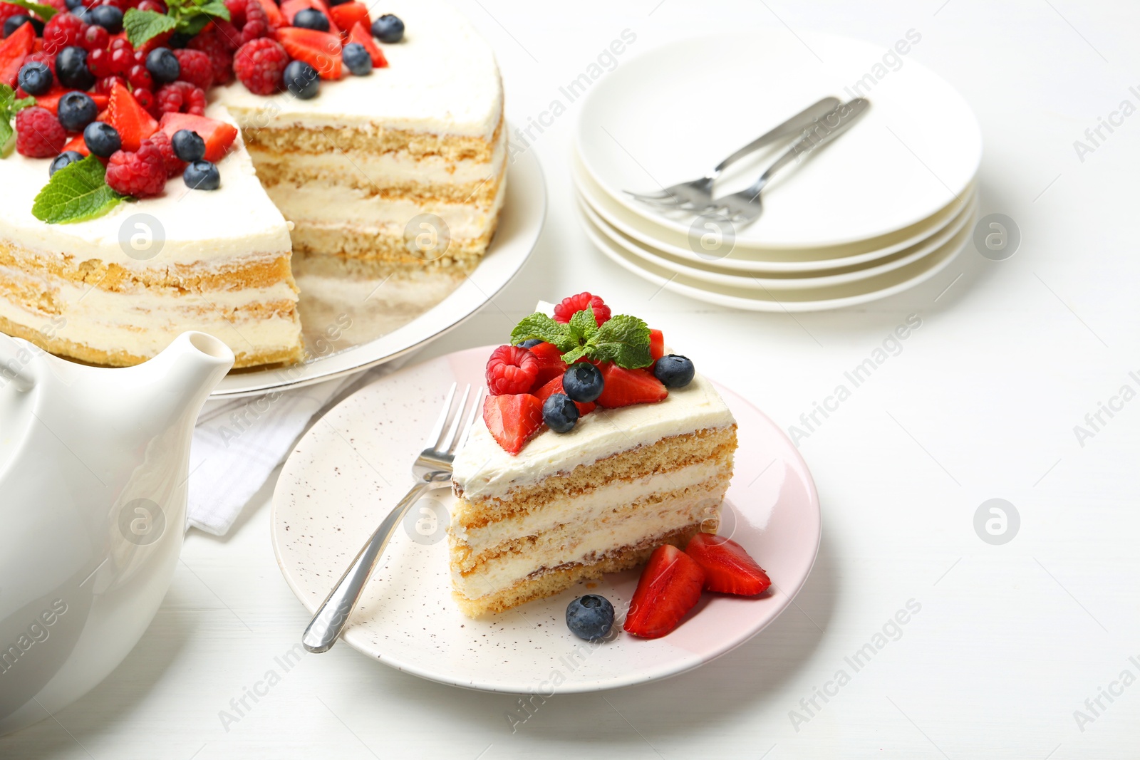 Photo of Tasty sponge cake with fresh berries and mint served on white table