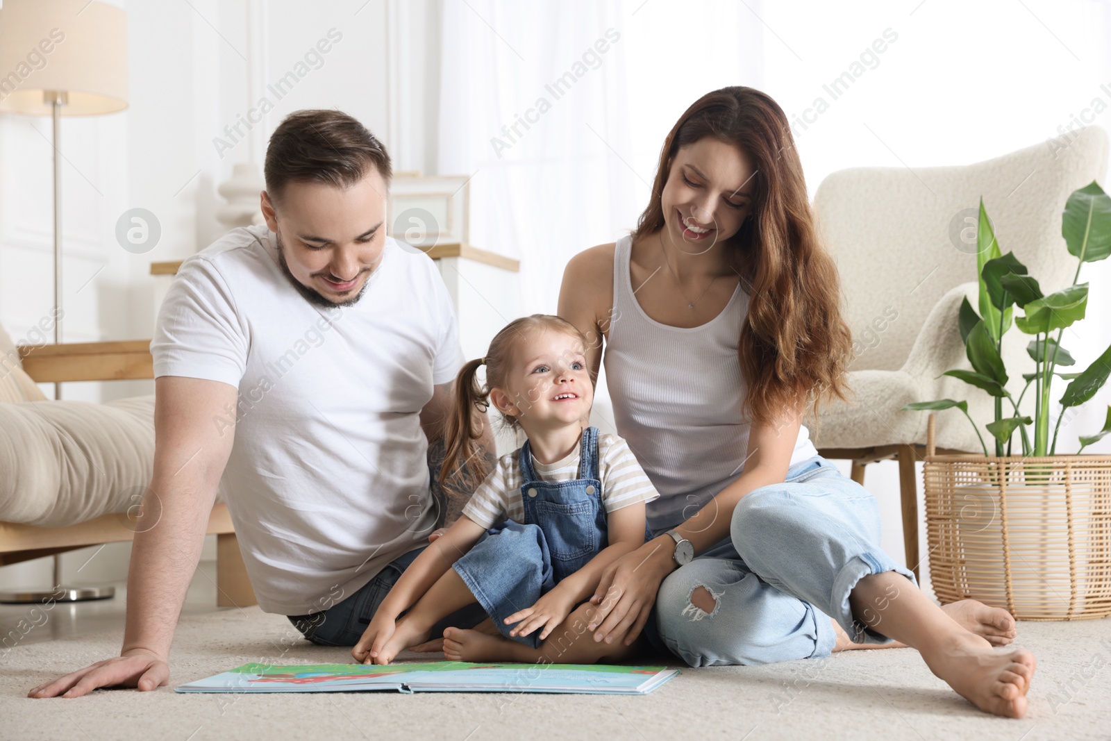 Photo of Happy family. Parents and their cute little daughter with book at home