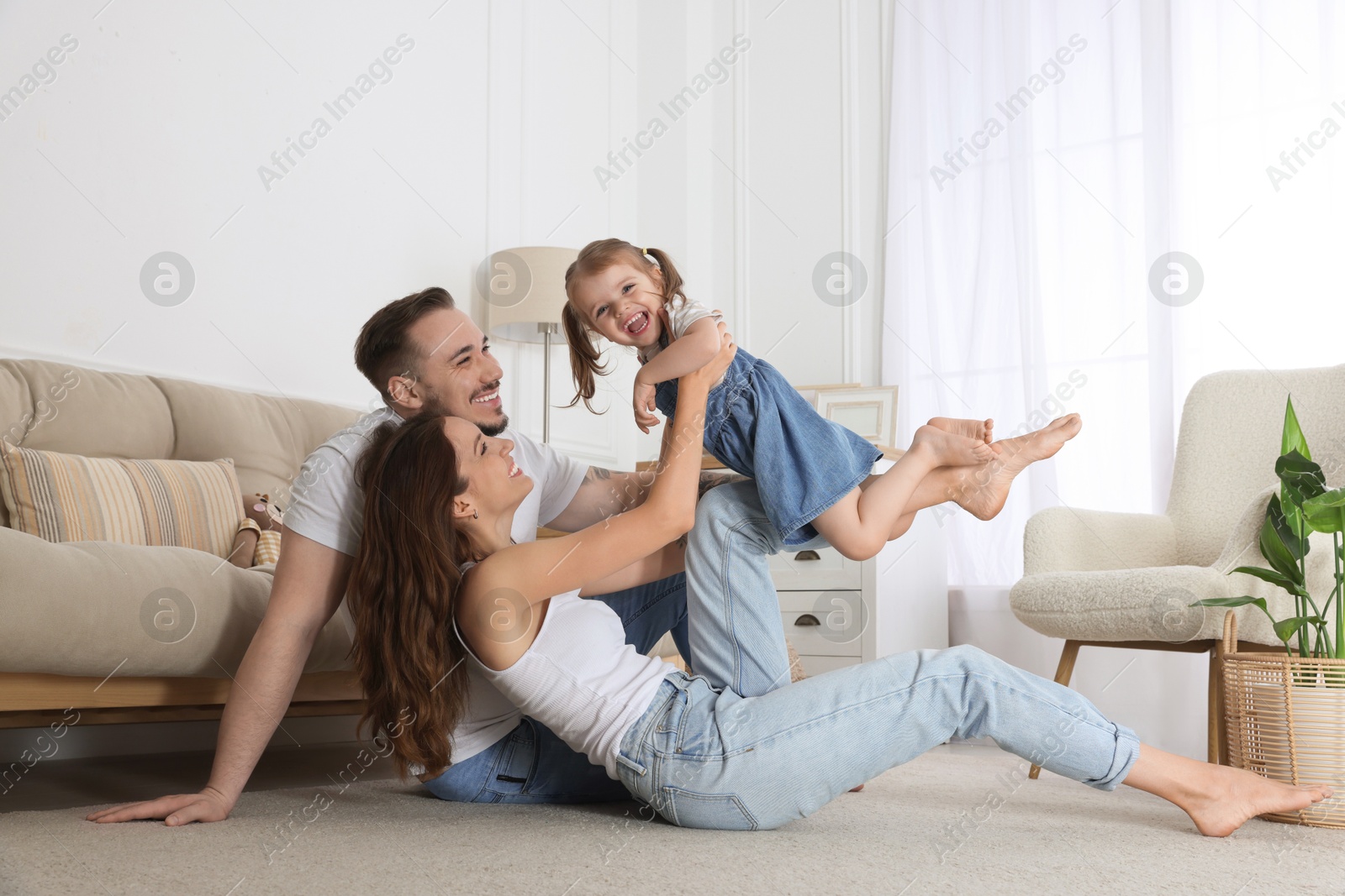 Photo of Happy family. Parents and their cute little daughter having fun at home