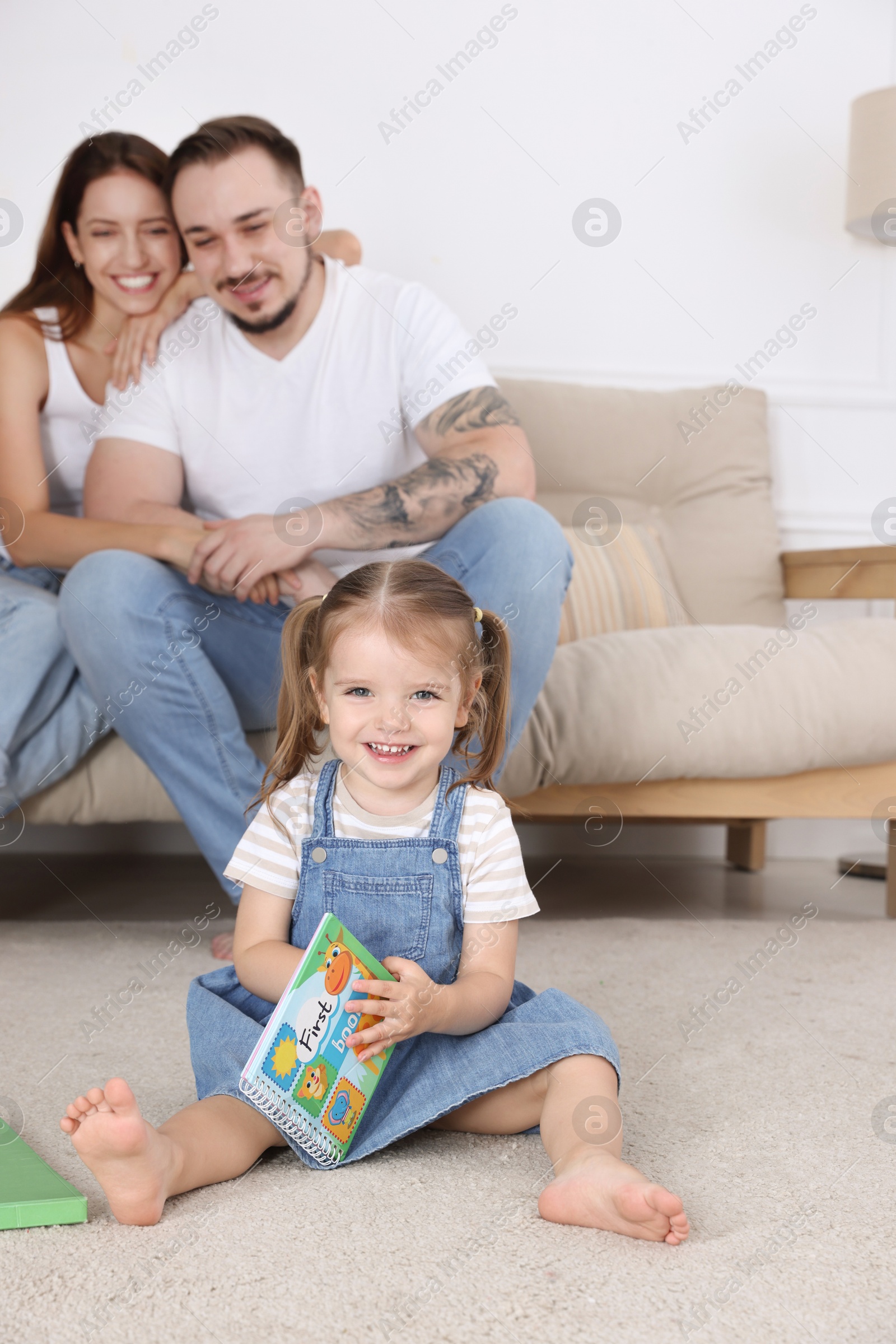 Photo of Happy family. Parents and their cute little daughter with book at home, selective focus