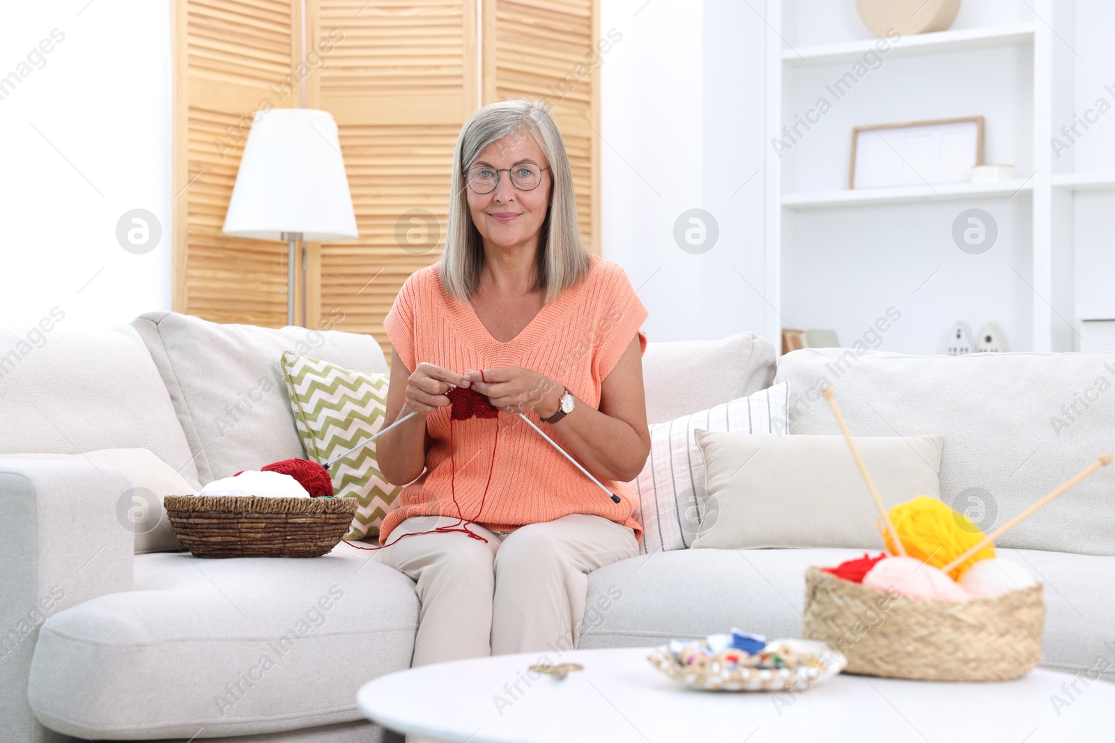 Photo of Beautiful senior woman knitting on sofa at home