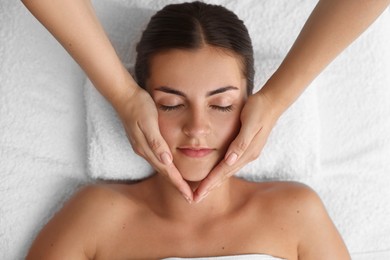 Photo of Attractive woman enjoying face massage, top view. Beauty procedure