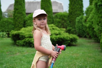 Photo of Cute little girl with hose in backyard