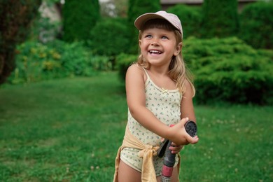 Cute little girl with hose in backyard