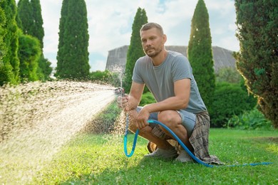 Man watering lawn with hose in backyard