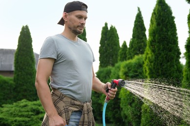 Man watering lawn with hose in backyard