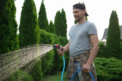 Man watering lawn with hose in backyard