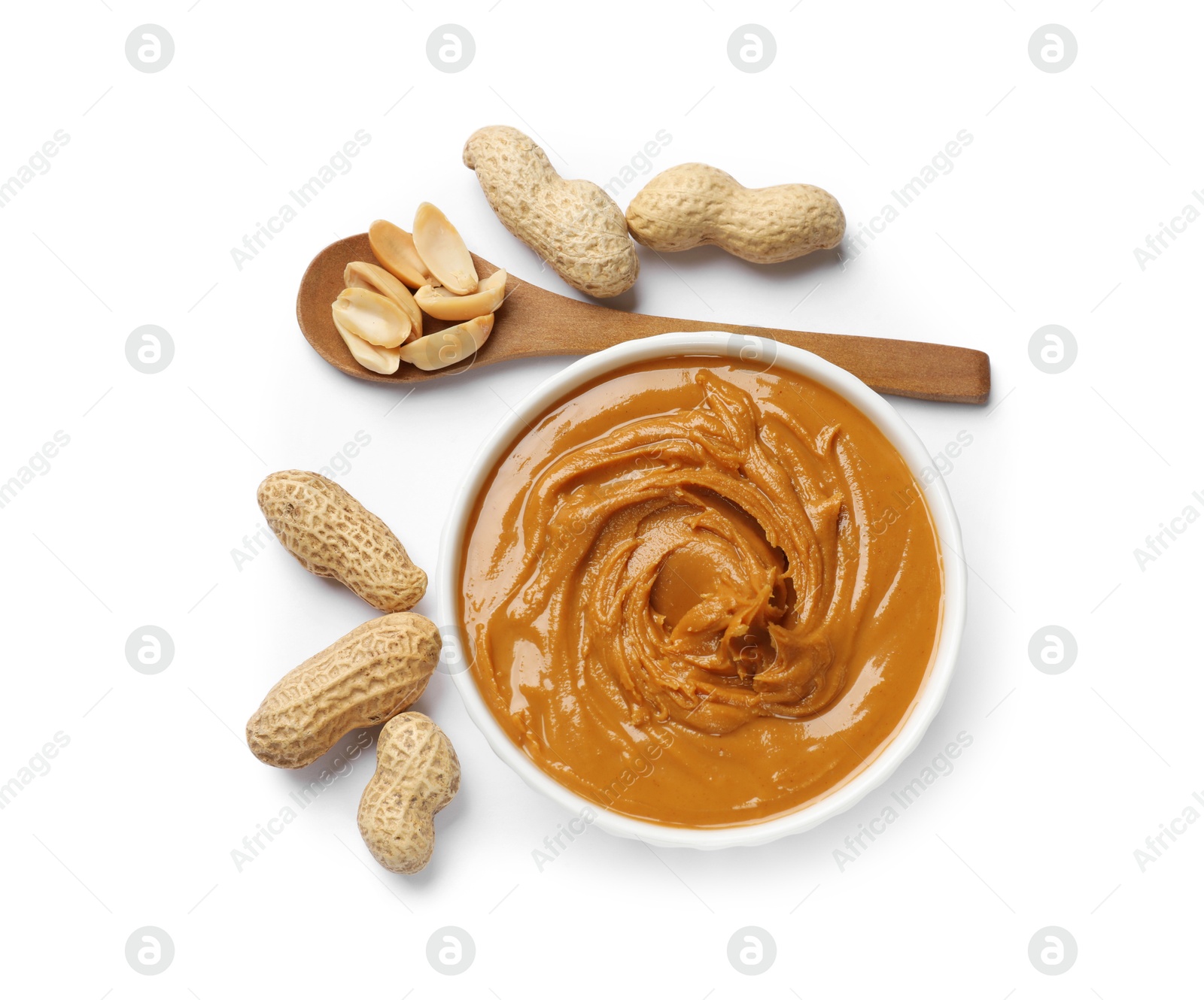 Photo of Tasty peanut butter in bowl, spoon and groundnuts isolated on white, top view