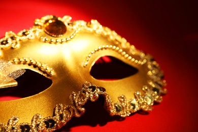 Beautiful golden carnival mask on red background, closeup