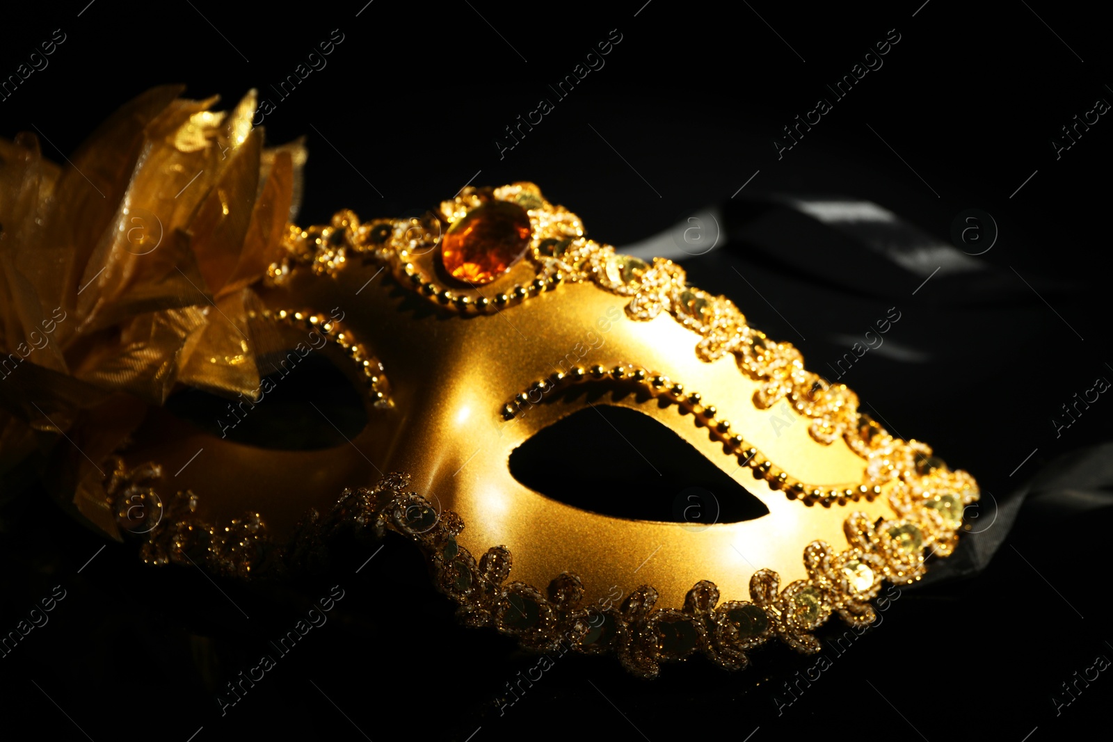 Photo of Beautiful golden carnival mask on black background, closeup