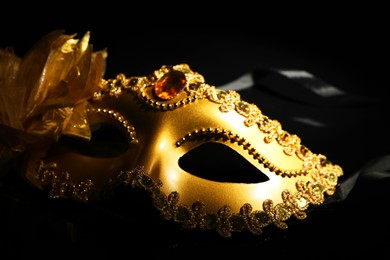 Photo of Beautiful golden carnival mask on black background, closeup