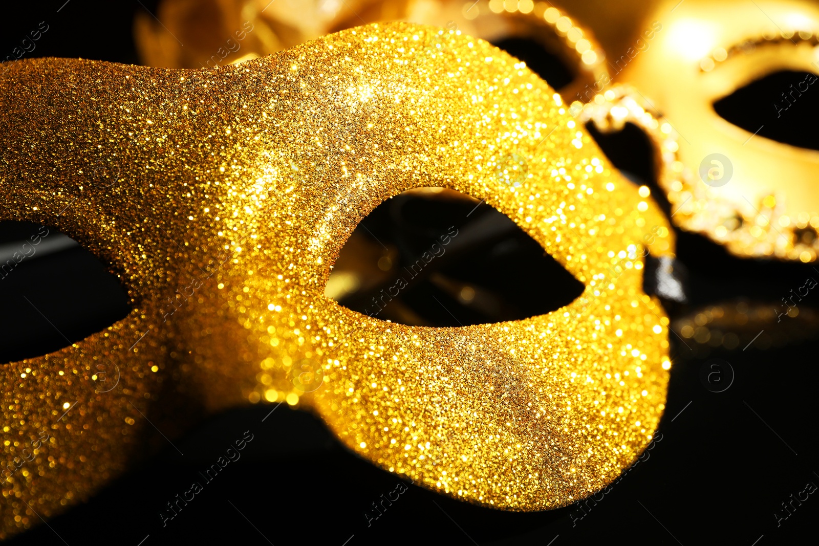 Photo of Beautiful golden carnival masks on black background, closeup