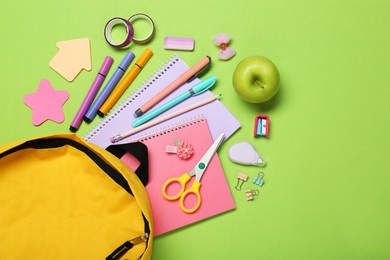 Backpack, different school stationery and apple on light green background, flat lay. Space for text