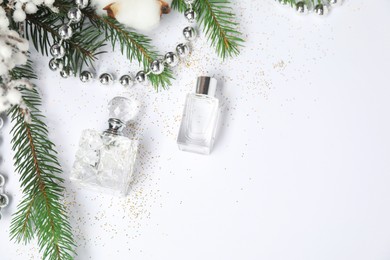 Christmas composition with perfume bottles on white background, flat lay. Space for text