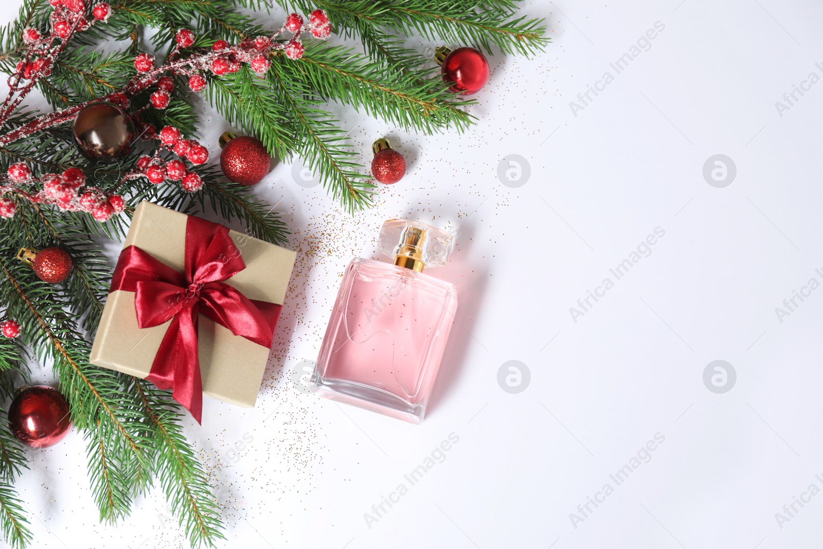 Photo of Christmas composition with perfume bottle on white background, above view. Space for text