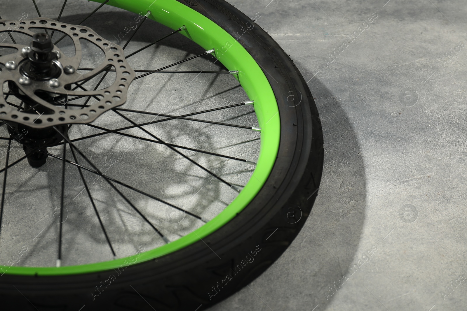 Photo of Bicycle wheel with tire on grey background, closeup