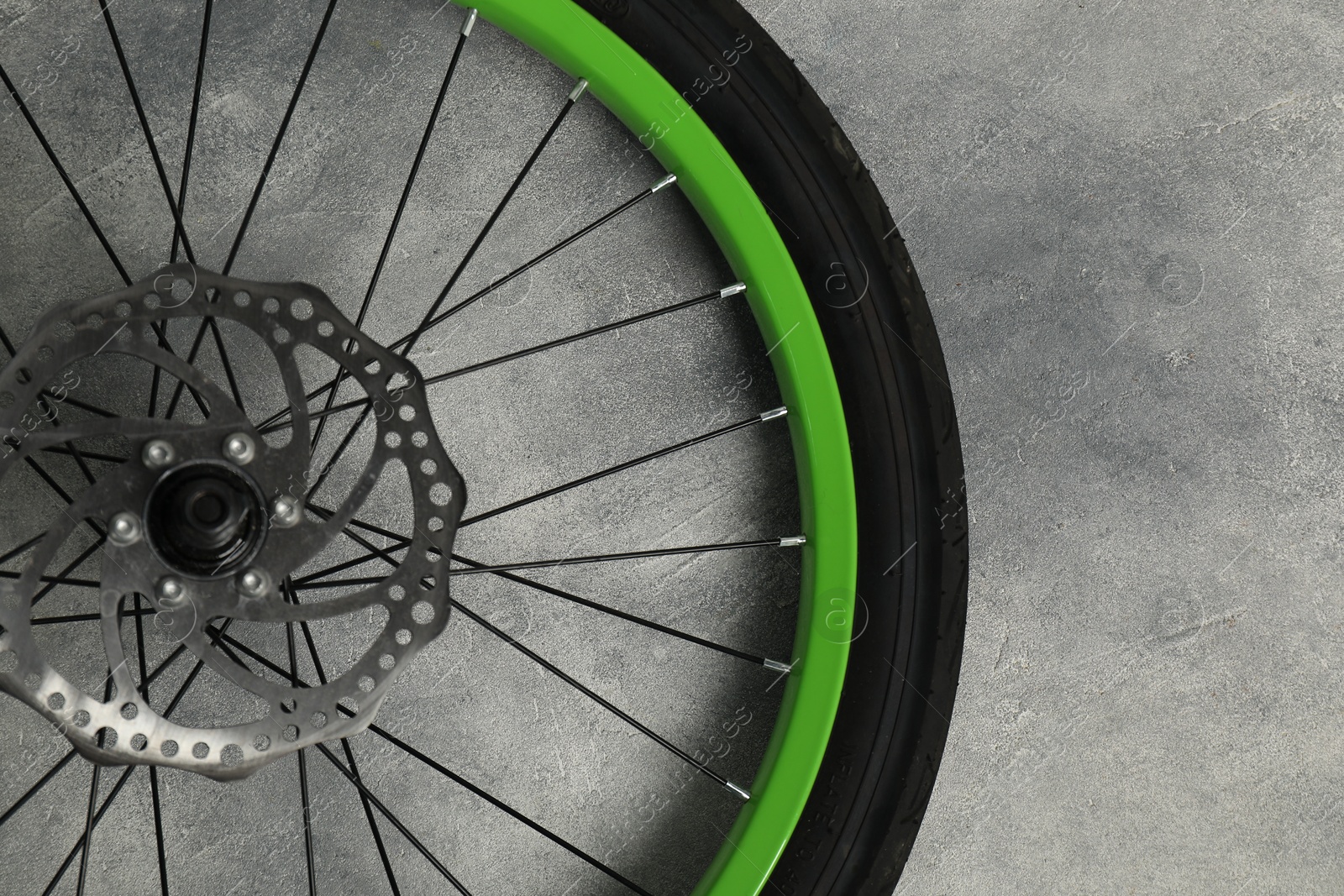 Photo of Bicycle wheel with tire on grey background, top view