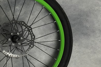 Bicycle wheel with tire on grey background, top view