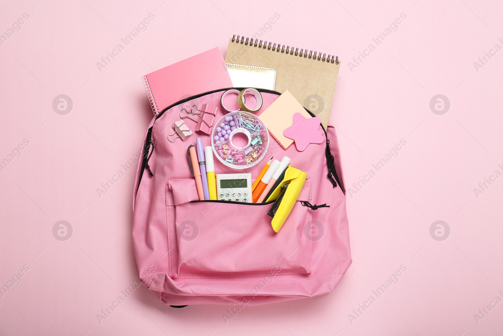 Photo of Backpack and different school stationery on pink background, top view