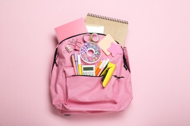 Photo of Backpack and different school stationery on pink background, top view