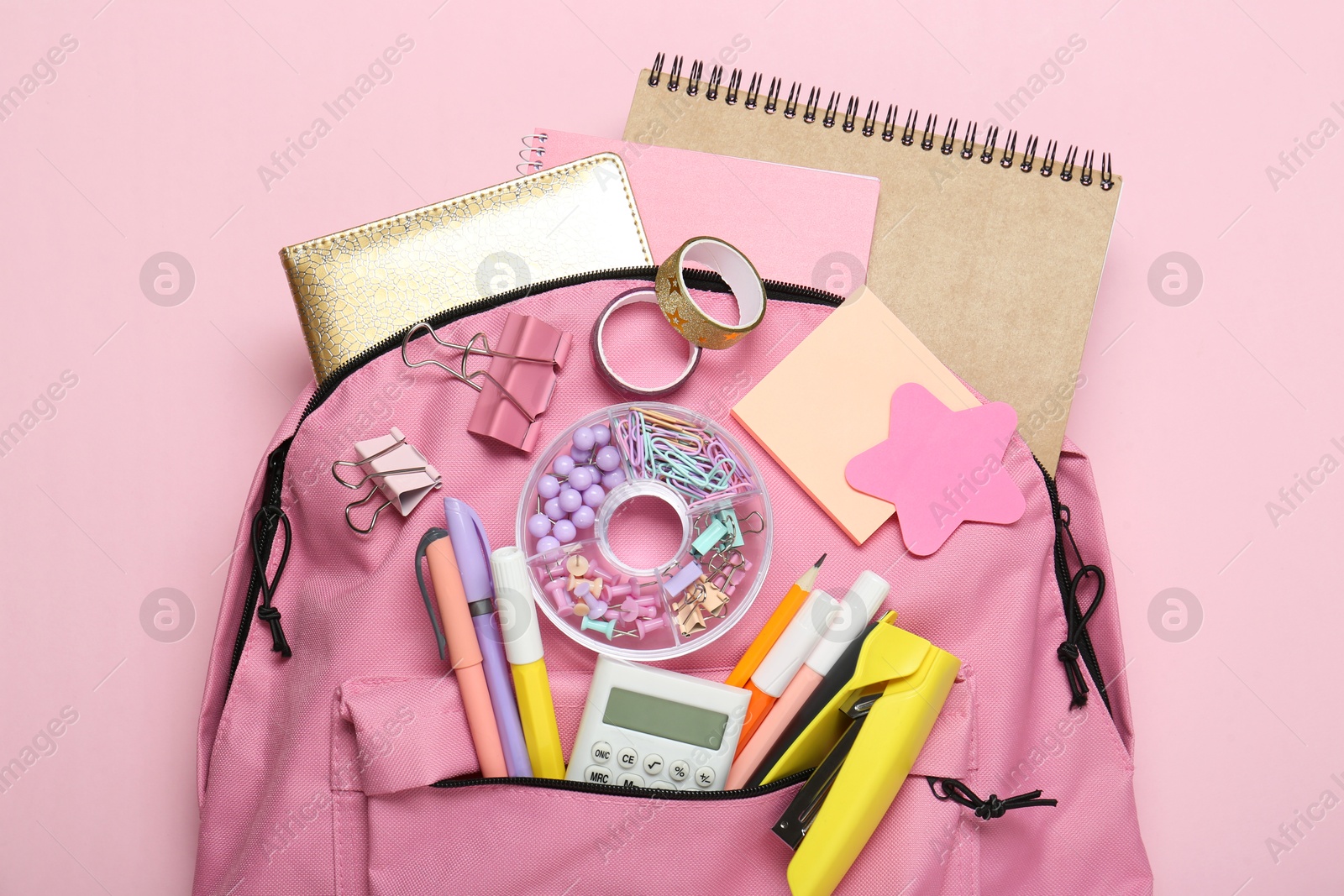 Photo of Backpack and different school stationery on pink background, top view