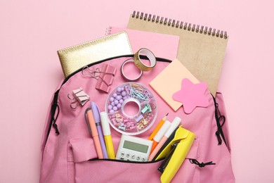 Photo of Backpack and different school stationery on pink background, top view