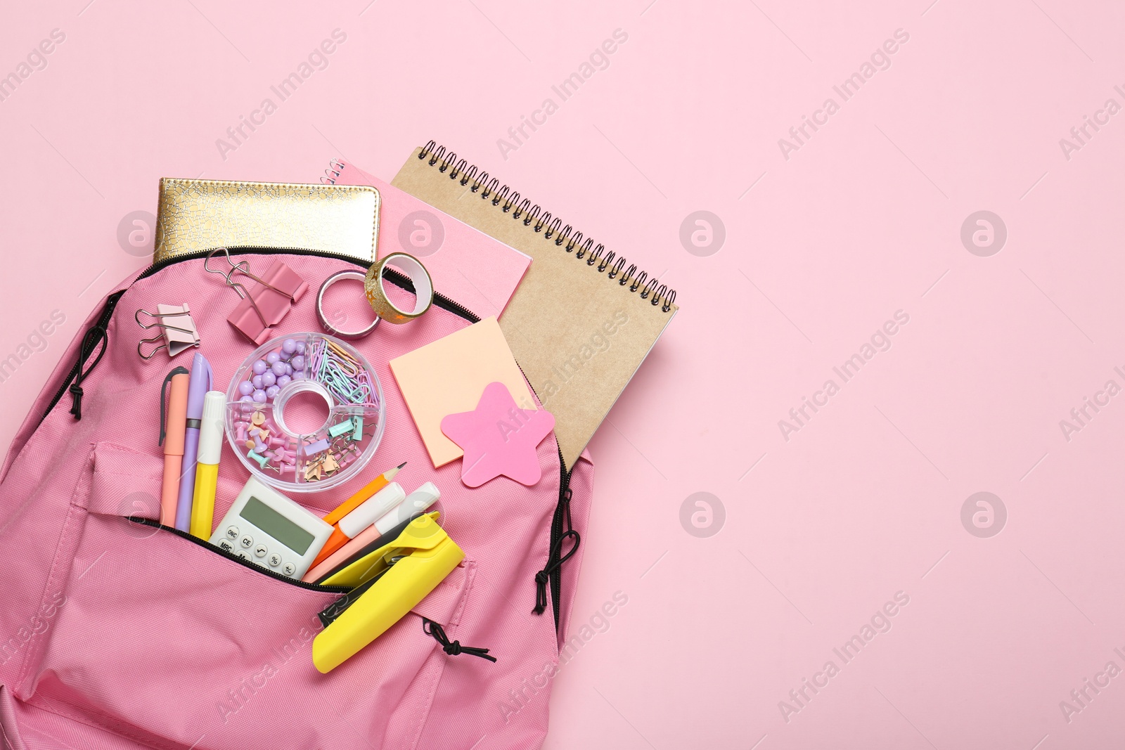 Photo of Backpack and different school stationery on pink background, top view. Space for text