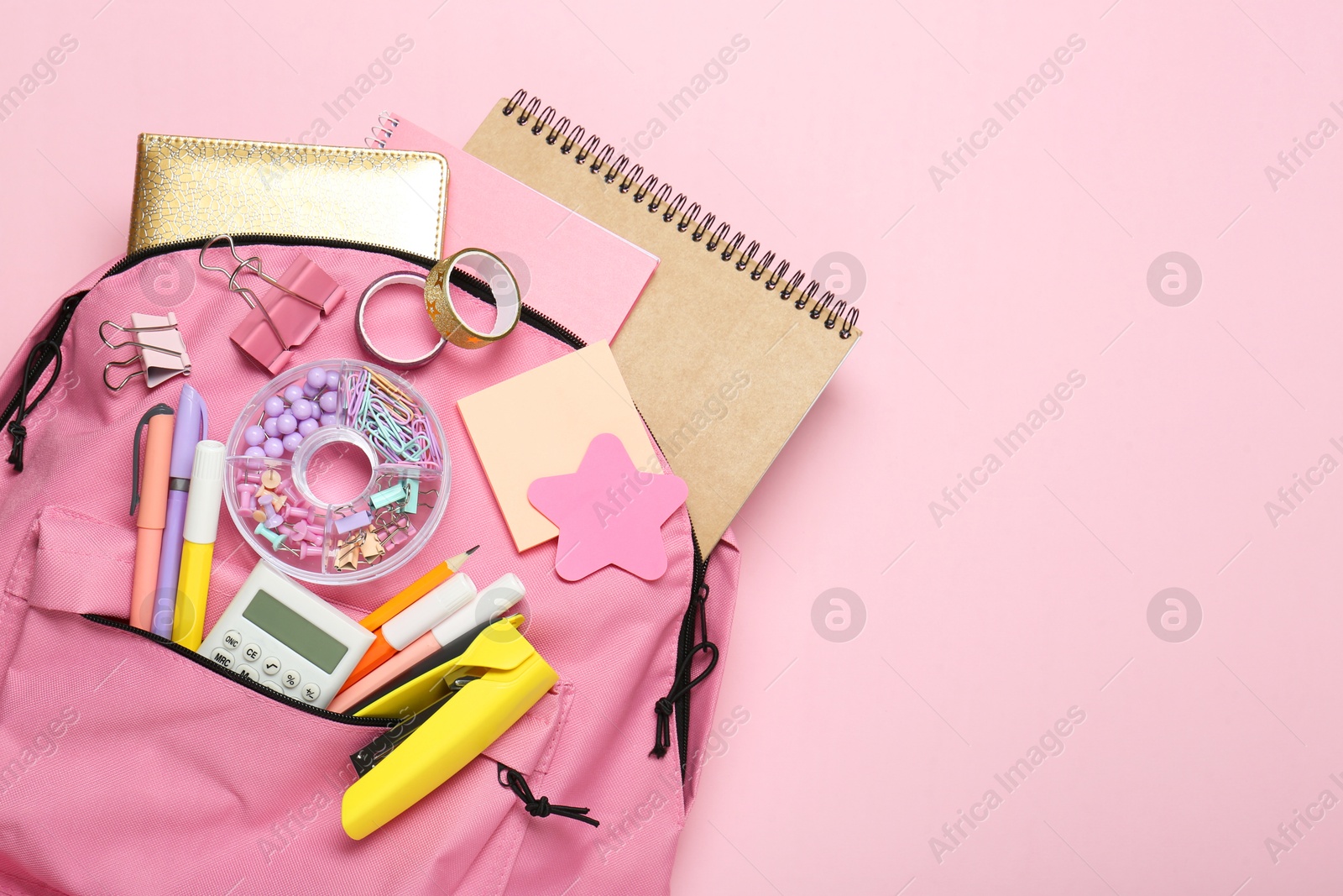 Photo of Backpack and different school stationery on pink background, top view. Space for text