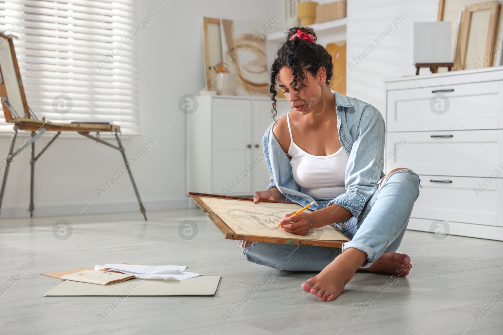 Photo of Woman drawing picture with pencil on floor in studio