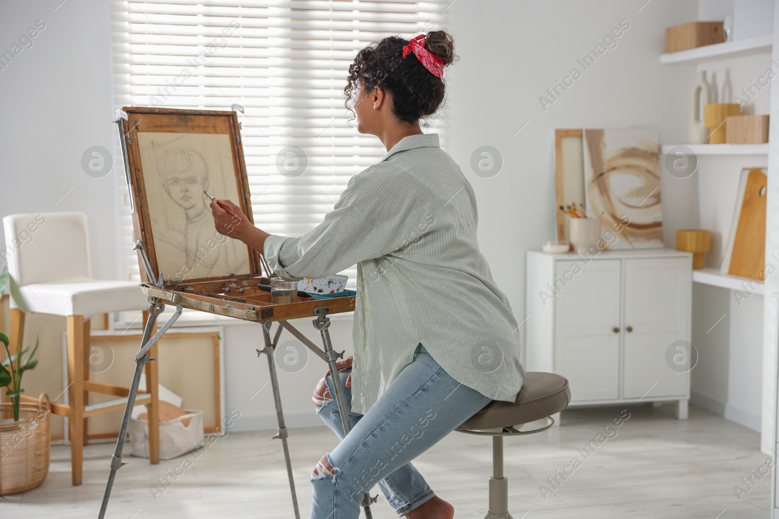 Photo of Beautiful woman drawing picture on canvas in studio