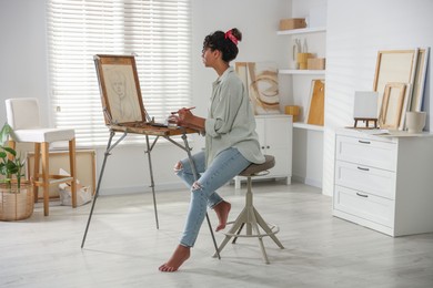 Beautiful woman drawing picture on canvas in studio