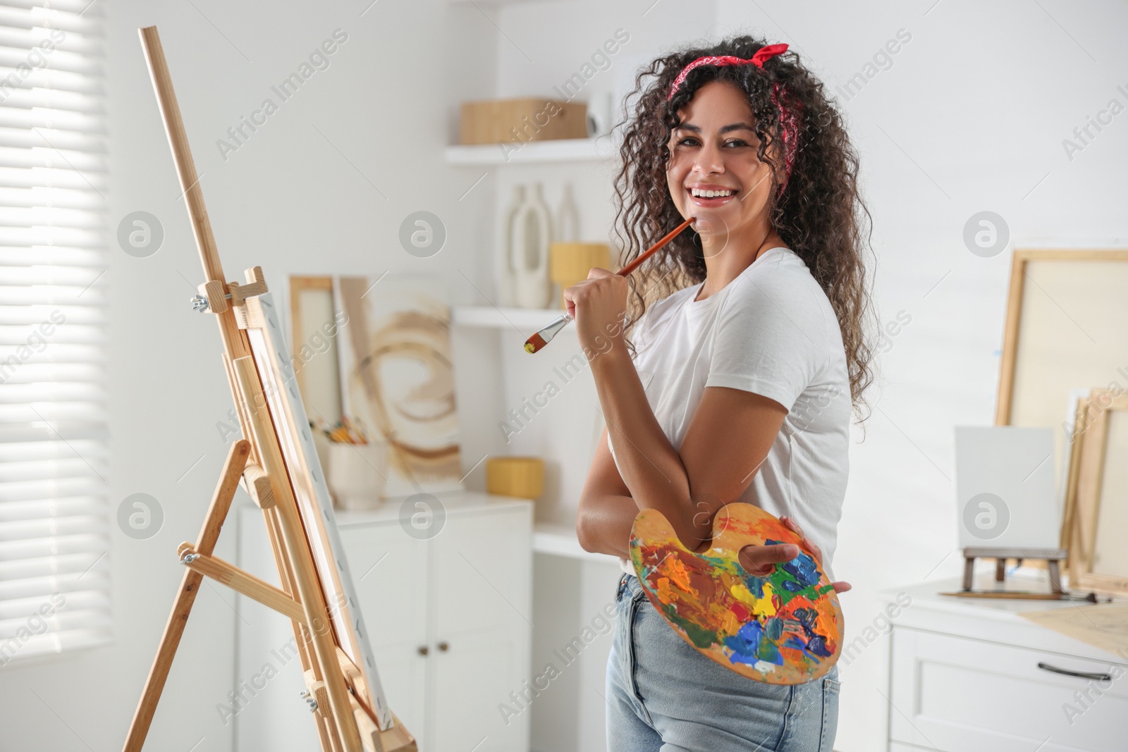 Photo of Smiling woman drawing picture on canvas in studio