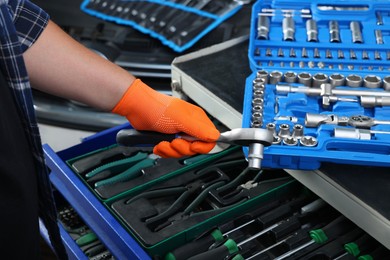 Auto mechanic with torque wrench and different tools at automobile repair shop, closeup