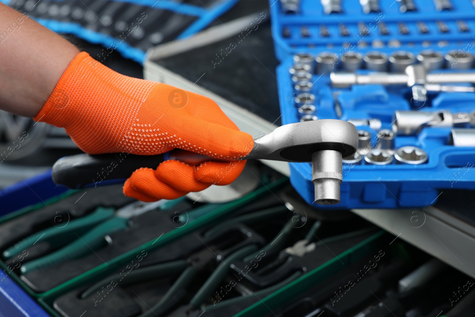 Photo of Auto mechanic with torque wrench and different tools at automobile repair shop, closeup