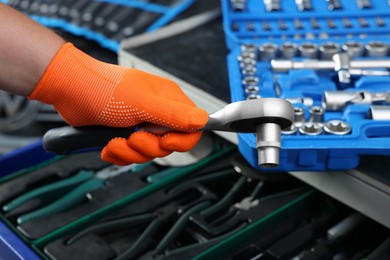 Auto mechanic with torque wrench and different tools at automobile repair shop, closeup