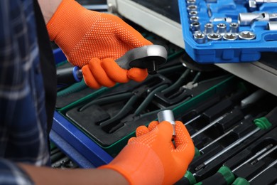 Auto mechanic with torque wrench and different tools at automobile repair shop, closeup