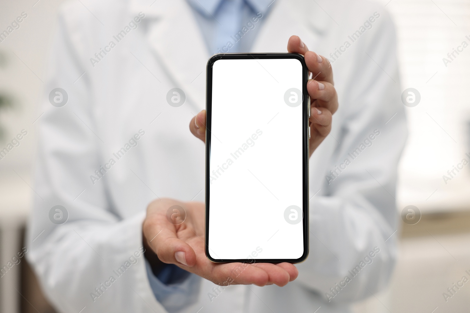 Photo of Doctor showing smartphone with blank screen in hospital, selective focus