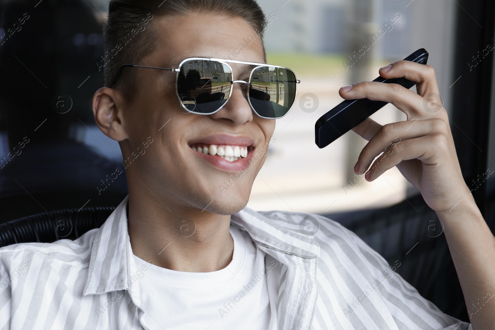 Photo of Young man with smartphone listening to voice message in outdoor cafe