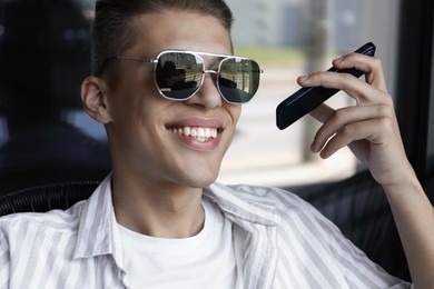 Young man with smartphone listening to voice message in outdoor cafe