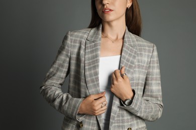 Beautiful woman with stylish jacket and watch on grey background, closeup