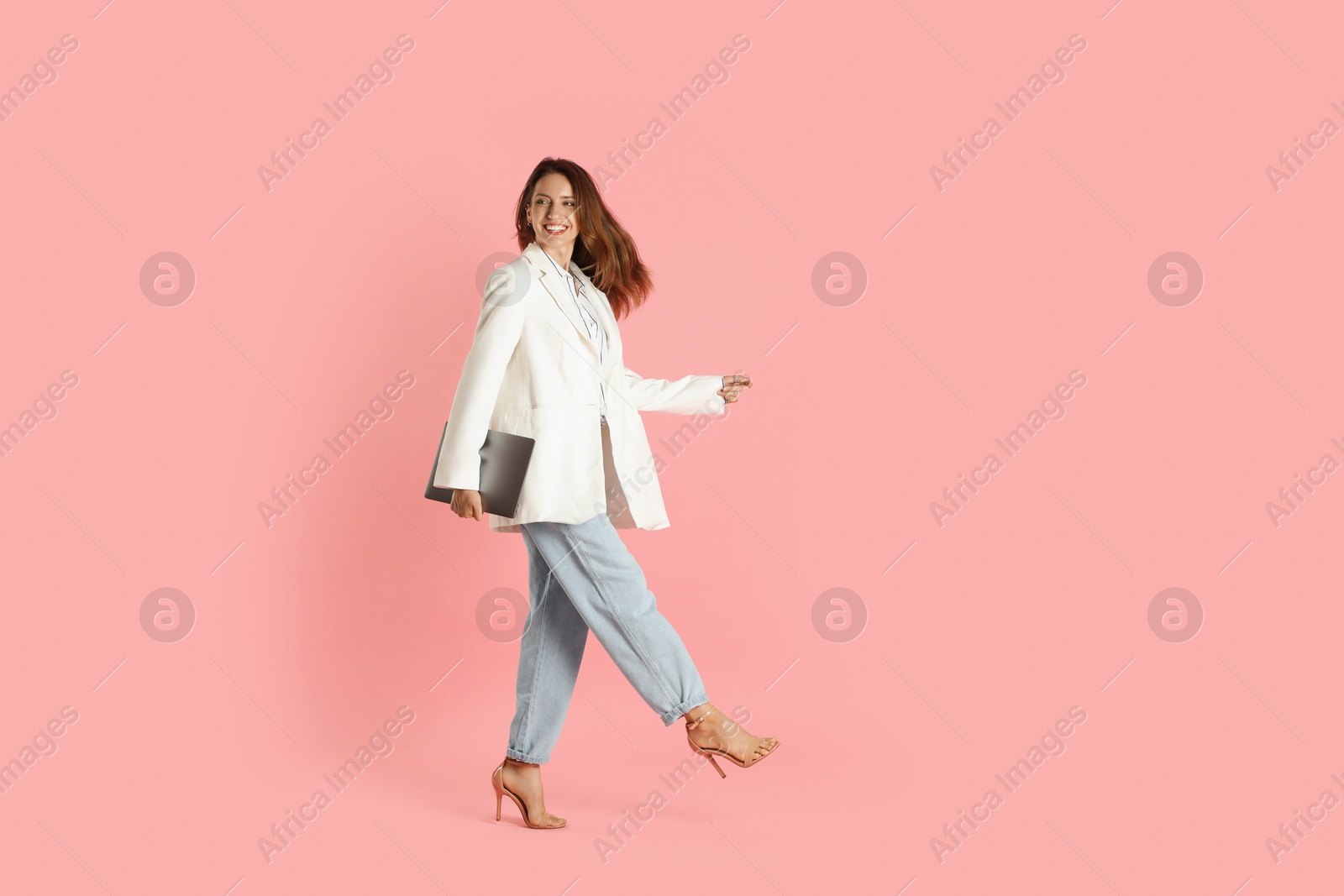 Photo of Beautiful woman in stylish white jacket with laptop on pink background, space for text